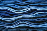 Side view of denim fabrics stacked upon one another in different shades of blue