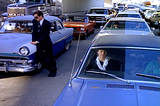 Cars standing in traffic. one man standing outside, leaning on a car