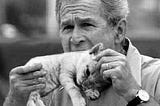 A black and white meme of George W. Bush eating a kitten.