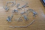 Several contorted paperclips sitting on a desk.