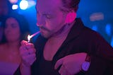 stylish man lighting cigarette, man smoking cigarette in a night club party