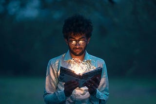 A young man reads from a magical-looking book