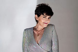 Middle aged woman smiles at the camera in a sparkly silver outfit