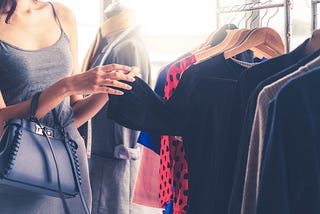 Woman looks through clothes rack in a store.