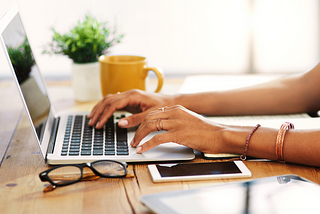 Cropped photo of unrecognizable woman working on laptop from Canva.