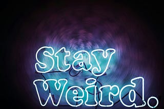 The words “Stay Weird” on a lit up purple, blue and black background