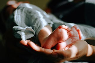 A newborn baby’s feet cradled in a mother’s hand.