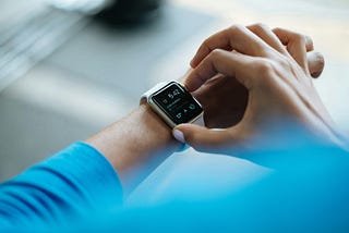 Close-up of a person wearing a smartwatch and adjusting the settings on its screen. The smartwatch displays the time as 5:42 and shows additional information, including steps taken and weather details.