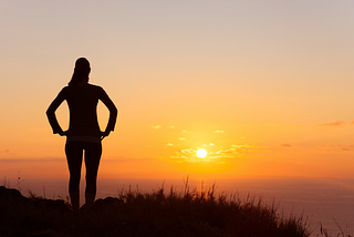 Sunrise beach scene with person in silhouette.