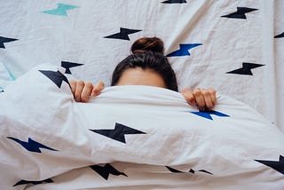 a lovely, young woman hiding her face in the blanket