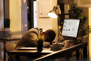 Tired drained entrepreneur sleeping on desk in startup office