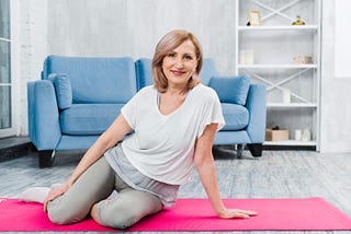 Portrait of a beautiful happy woman sitting on pink yoga mat