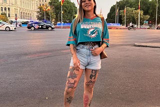 A woman stands in the road in Madrid, smiling.