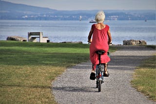 Image of pensioner wearing red dress & riding a bike by pasja1000 on Pixabay