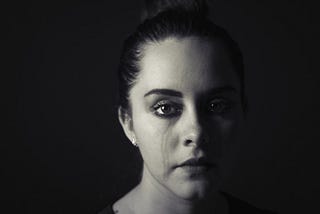 Woman, sad, tear tracks, face in shadow, monochrome