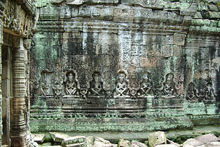 Temple wall, covered in sitting Buddhas and green lichen