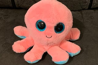 smiling pink octopus stuffed animal with large blue eyes