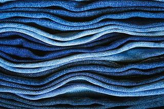 Side view of denim fabrics stacked upon one another in different shades of blue