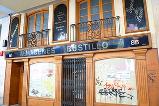 A Spanish shop front, the windows boarded up and covered in graffiti