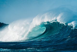 This is a photo of an ocean’s tide. This is a high tide. The water is blue. We can see the sky in the background showing the evening time. It seems that the high tide is due to the moon's presence.