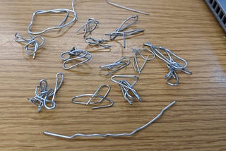 Several contorted paperclips sitting on a desk.