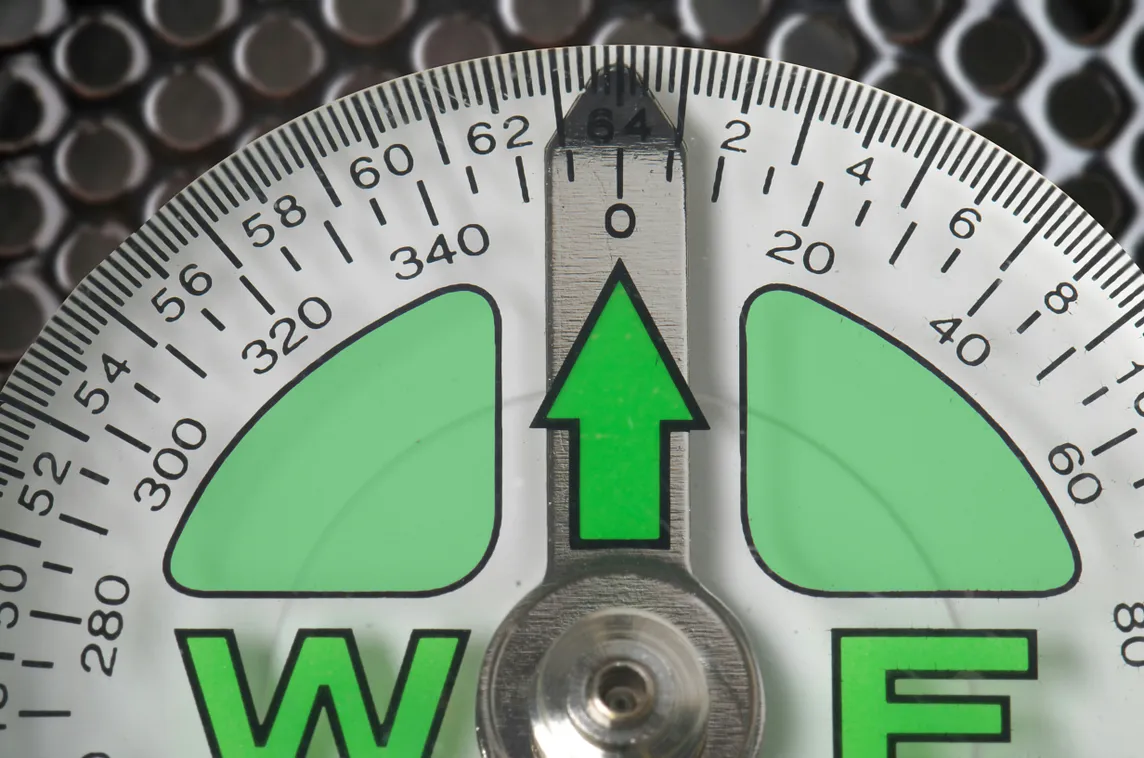 A measurement dial marked with two different scales. A green arrow points to 64/0.