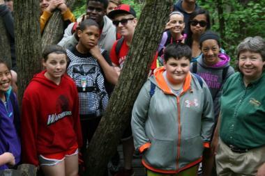 Students and a park naturalist pose around a tree