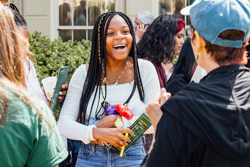 A student speaks with a team member at table at an event fair.