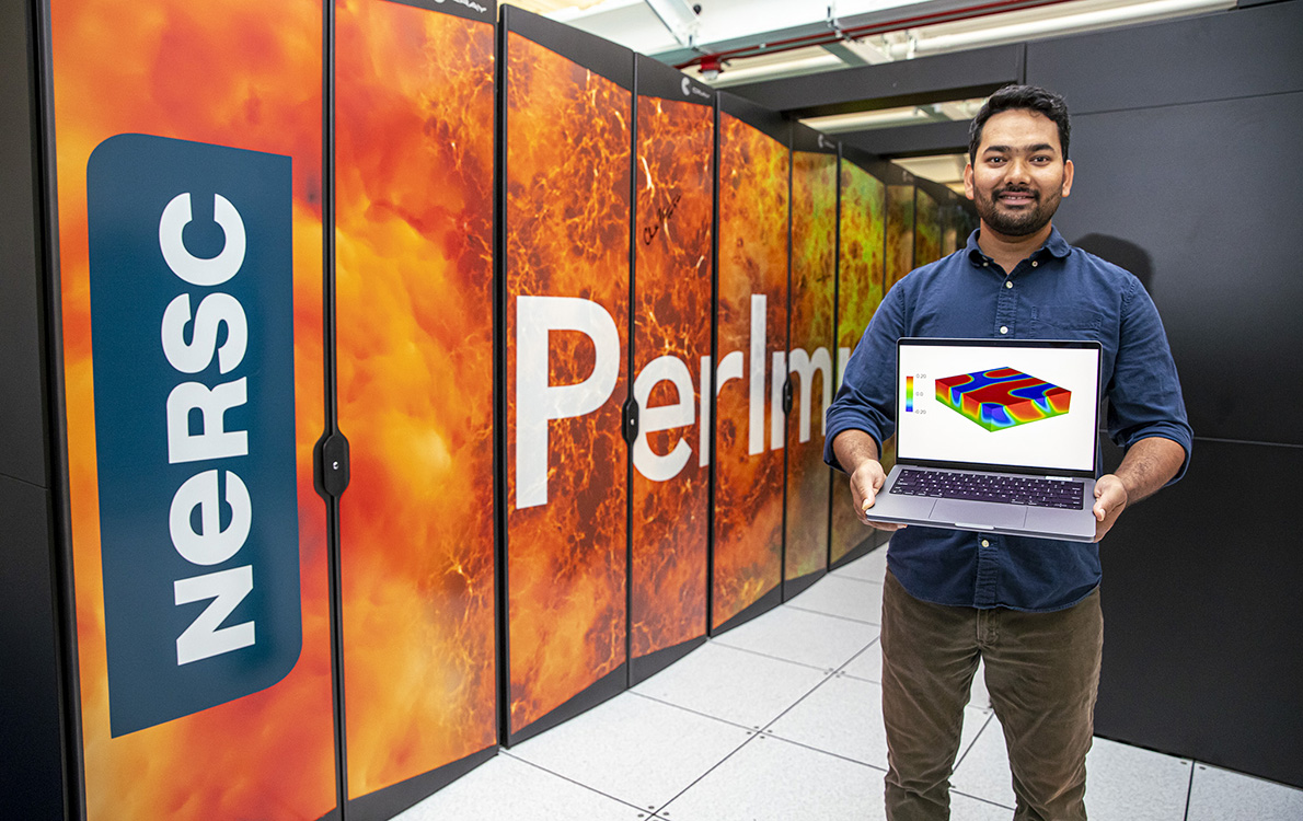 Prabhat Kumar holding a computer with a simulation in front of a super computer.