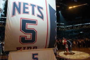 Jason Kidd huddles with his son as the banner bearing his name in number is lifted to the rafters at Barclays Center.