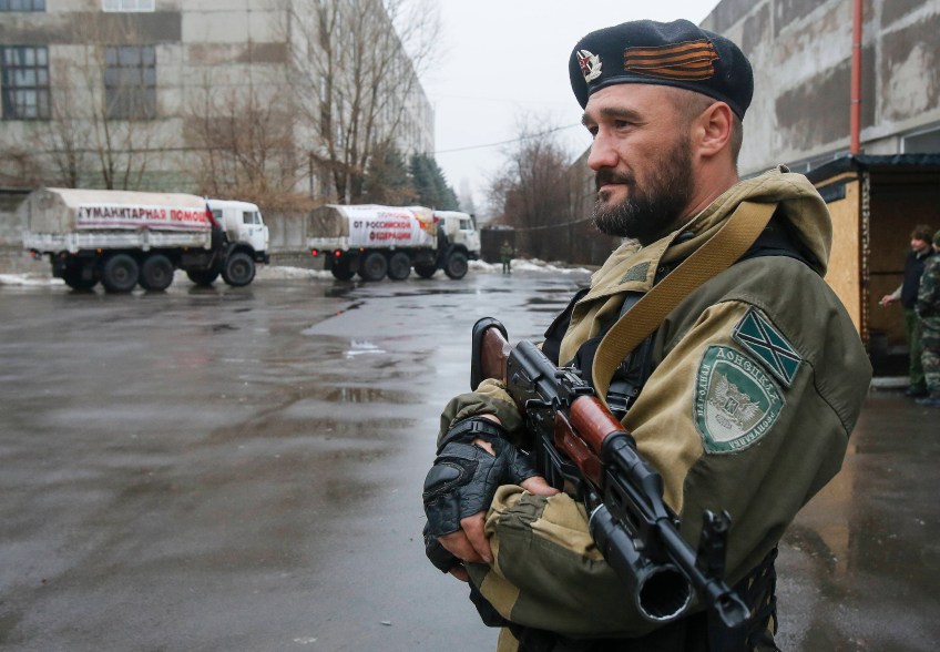 A pro-Russian-separatist patrols the street in front of Russian humanitarian trucks in Makiivka (Makeyevka) in Donetsk region, December 12, 2014. According to Russian media, over 50 trucks arrived in Donetsk while another 80 trucks arrived in Luhansk. REUTERS/Maxim Shemetov (UKRAINE - Tags: POLITICS CONFLICT SOCIETY)