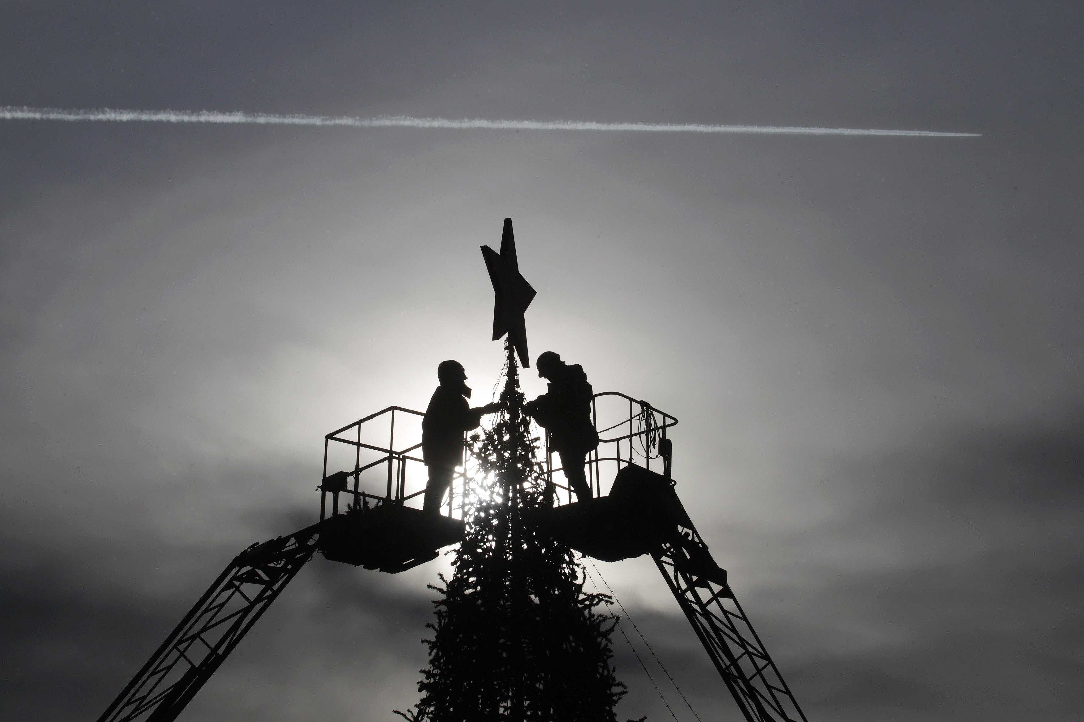 Workers decorate a Christmas tree at Lenin’s Square as a plane passes by in Stavropol