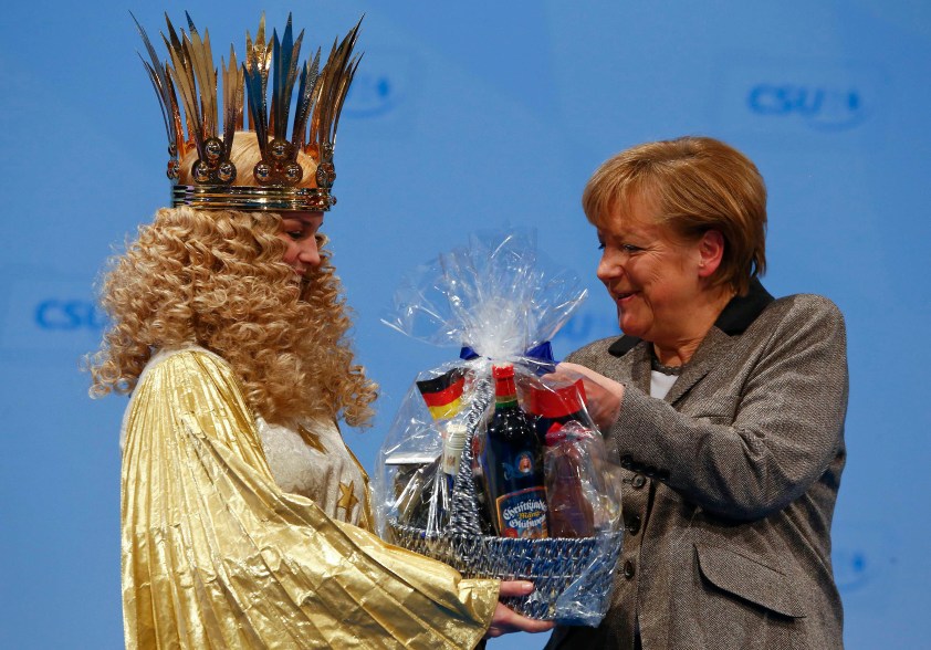 Angela Merkel, German chancellor and leader of the Christian Democratic Union party CDU receives a present of Teresa Treut (L), this year's gold-foiled Christ Child of the world's most famous Christmas market of Nuremberg, following her key-address at the party congress of the CDU's sister party, Bavaria's Christian Social Union party CSU in Nuremberg December 12, 2014. REUTERS/Michael Dalder (GERMANY - Tags: POLITICS TPX IMAGES OF THE DAY ENTERTAINMENT SOCIETY TRAVEL)