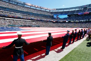 Members of the military hold a large American flag over the field before a game between the Bills and Jets at MetLife Stadium.