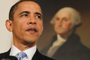 Barack Obama stands in front of a portrait of George Washington