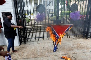 Members of the Mississippi Poor People's Campaign burn a Confederate battle flag at the Governor's Mansion in Jackson, Miss.