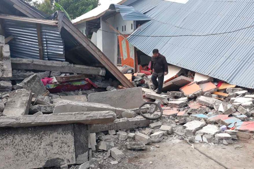 A man walks debris from destroyed houses in an area affected by an earthquake at Sajang village.