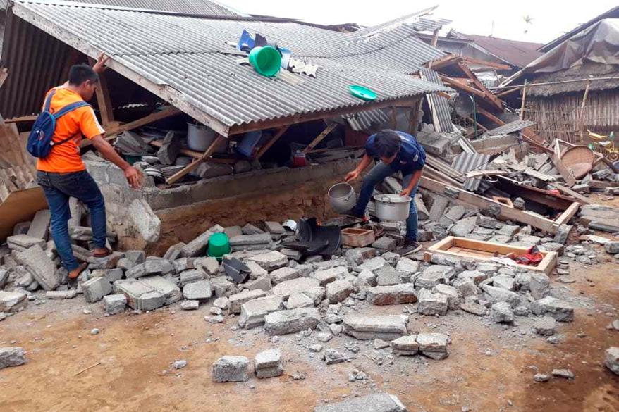 A man walks debris from destroyed houses in an area affected by an earthquake at Sajang village