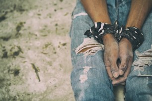 A man with his hands tied together with rope.