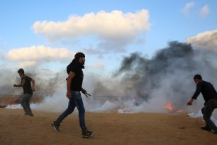 Protesters try to throw back teargas canisters fired by Israeli troops near the fence of the Gaza Strip border with Israel.