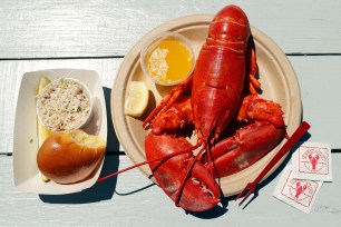 A cooked lobster is served with butter, coleslaw and bread.