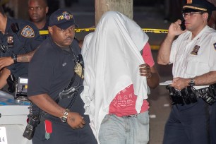 Police escort an off-duty officer, Ritchard Blake, with a sheet over his head.