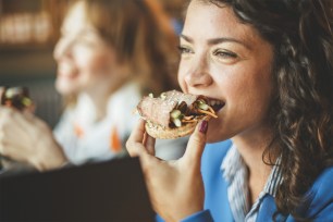 Young woman eating a fancy piece of toast at a cafe.