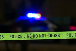 Police tape in front of a police car with lights on