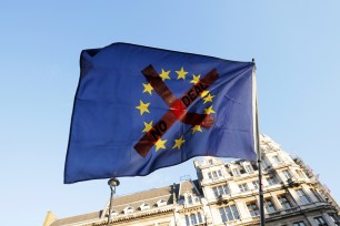 Protesters fly the flag of the European Union with an 'X' through it