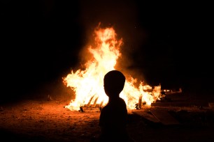 Child in front of a camp fire.