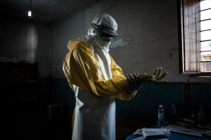 A health worker puts on his personal protective equipment before entering the red zone