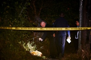 Investigators examine what appears to be a body wrapped in a carpet at the scene of a homicide in the vicinity of Sedgwick Avenue and W. 183rd.