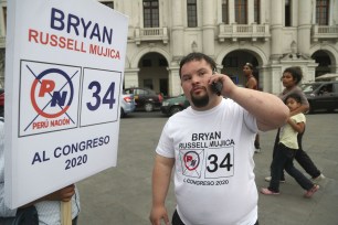 Bryan Russell takes a call as he campaigns for Congress in Lima, Peru.