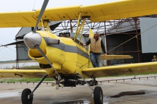 Parishioners gather around a crop duster plane carrying more than 100 gallons of holy water